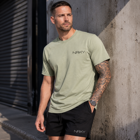 Man wearing a green t-shirt with 'NRKY' logo leaning against a concrete wall.