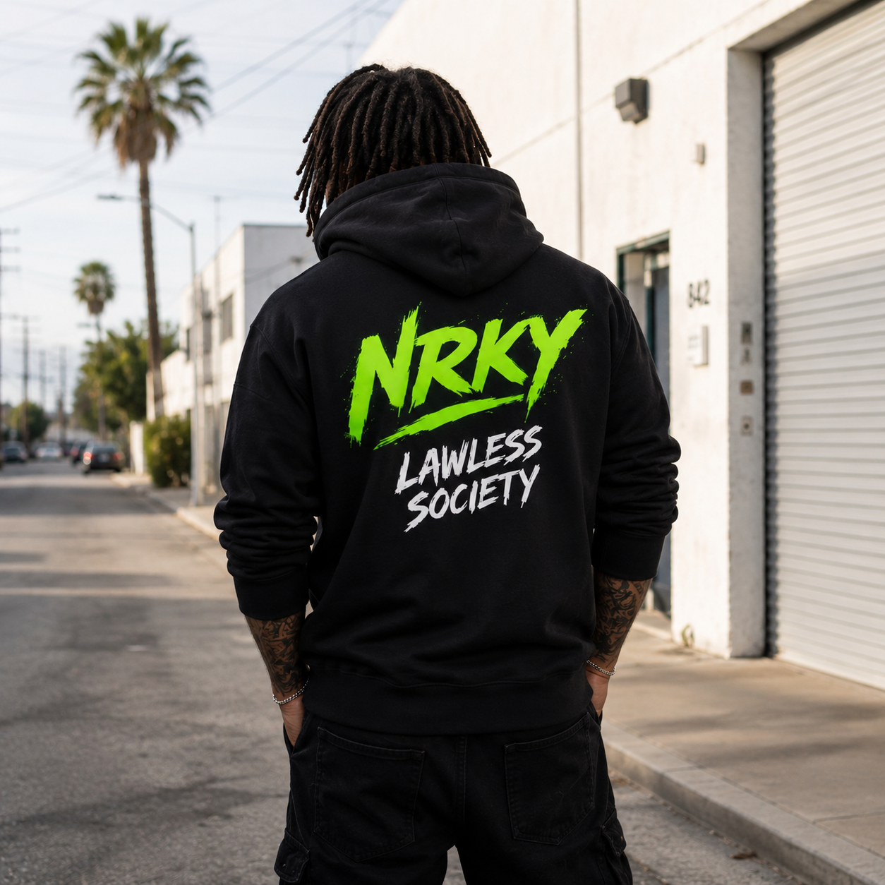 Person wearing a black hoodie with 'NRKY Lawless Society' text in green and white, standing on a street.